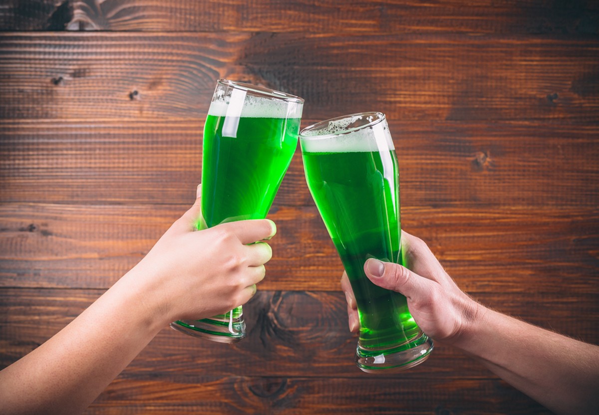 St Patrick's Day concept two mug on hands green beer against wooden background