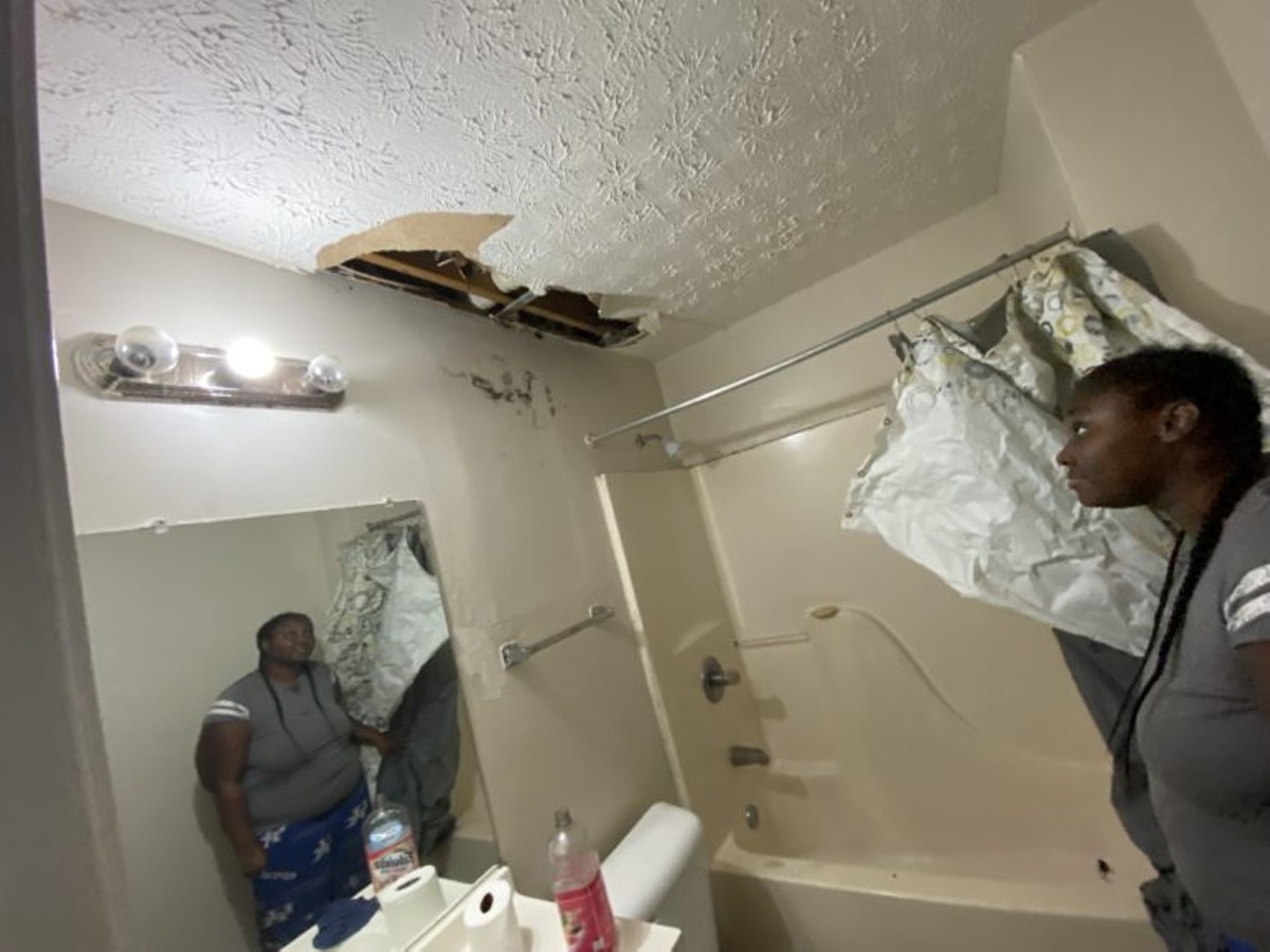 Shalonda Forney in her bathroom, looking at busted ceiling that dropped a mouse in her tub when it caved in.