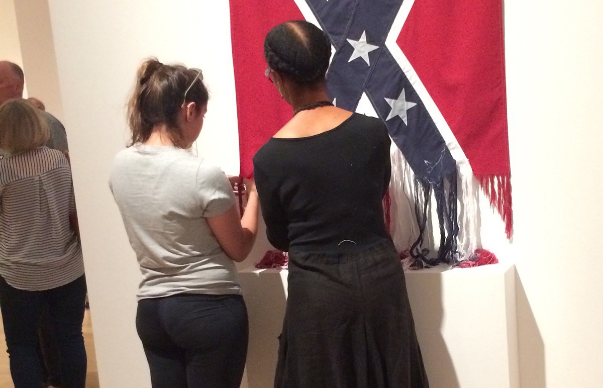 Sonya Clark (right) unraveled a Confederate flag at the Speed Museum and allowed patrons to help.
