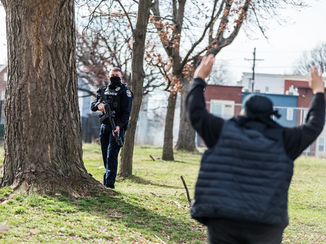 A protester stood with their hands up as a police officer held a gun while protesters marched through downtown.