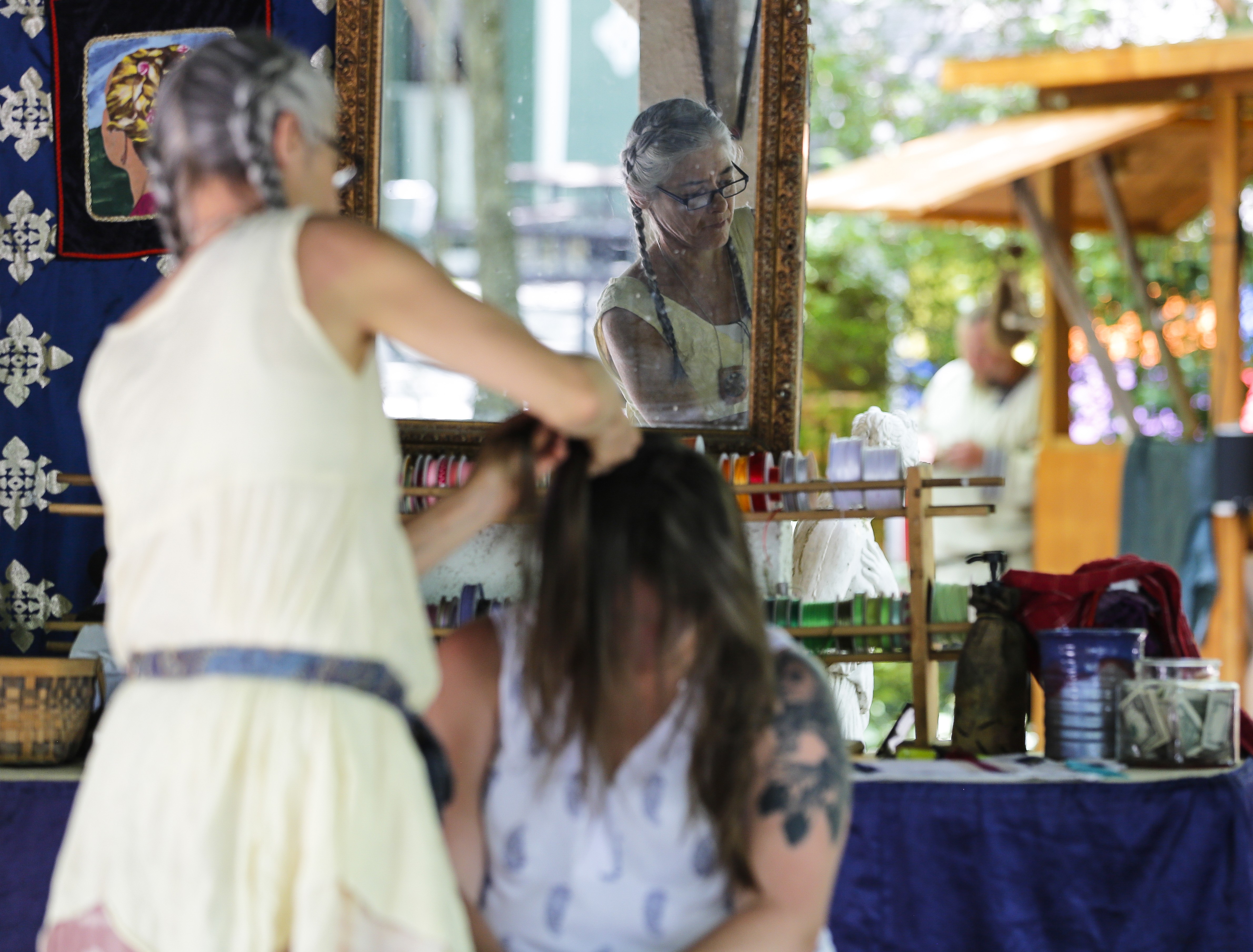 A festival goer gets her hair braided at Braided Image in the Briarwood Forrest