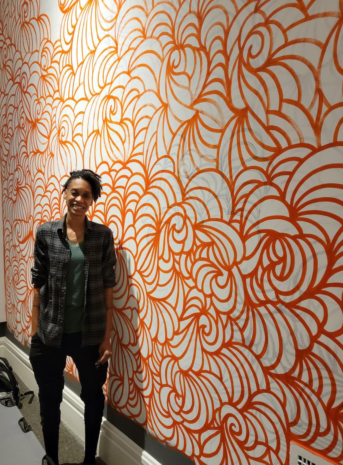 Carnegie's Artist-in-Residence Alexis "STIX" Brown stands against the "Anxiety" Wall.