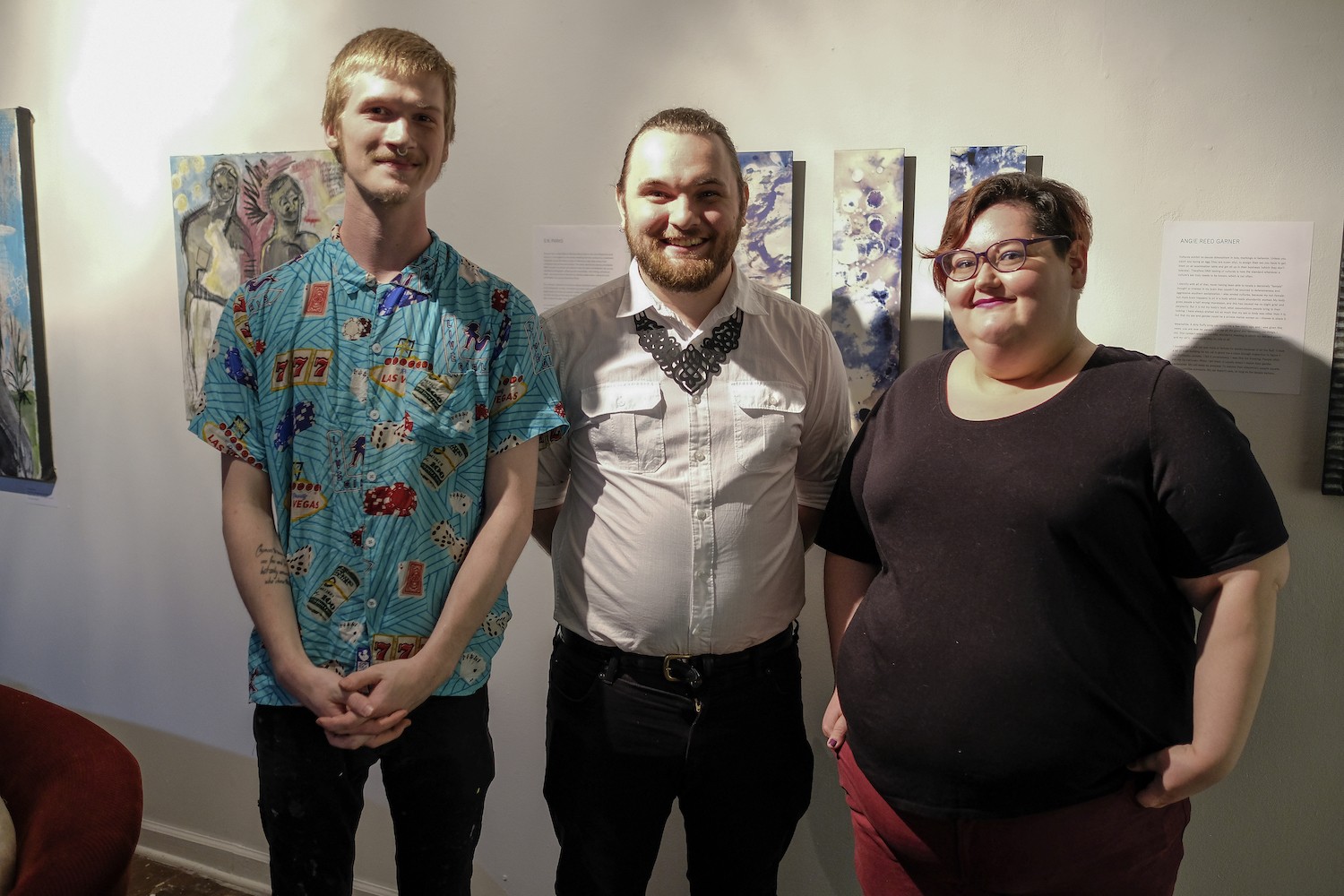 (From left to right) Curators of the Queer Voices art exhibit John Faughender, Kevin Warth, and S.N. Parks pose for a group photo in front of some of the art work.