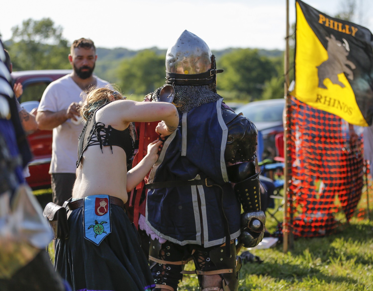 A knight gets components of his armor checked before he enters the ring.