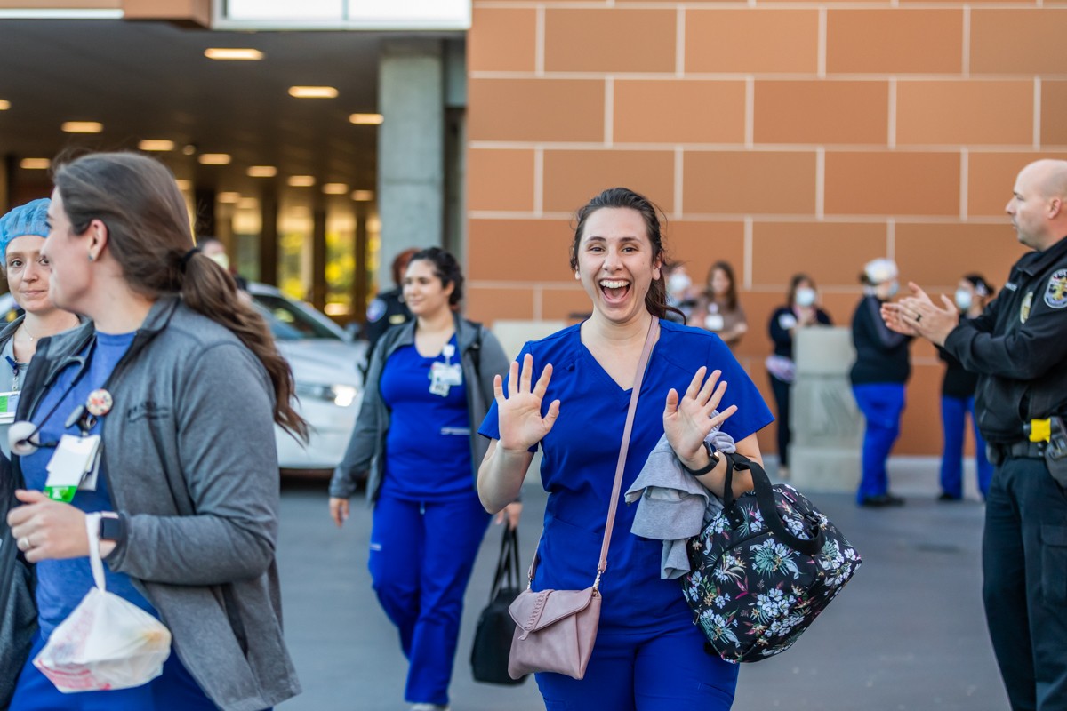 Registerned Nurse Andrea Shpilberg gave a wave as she and other healthcare workers ended their shifts on Tuesday and were met with applause from police officers and fire fighters. - KATHRYN HARRINGTON