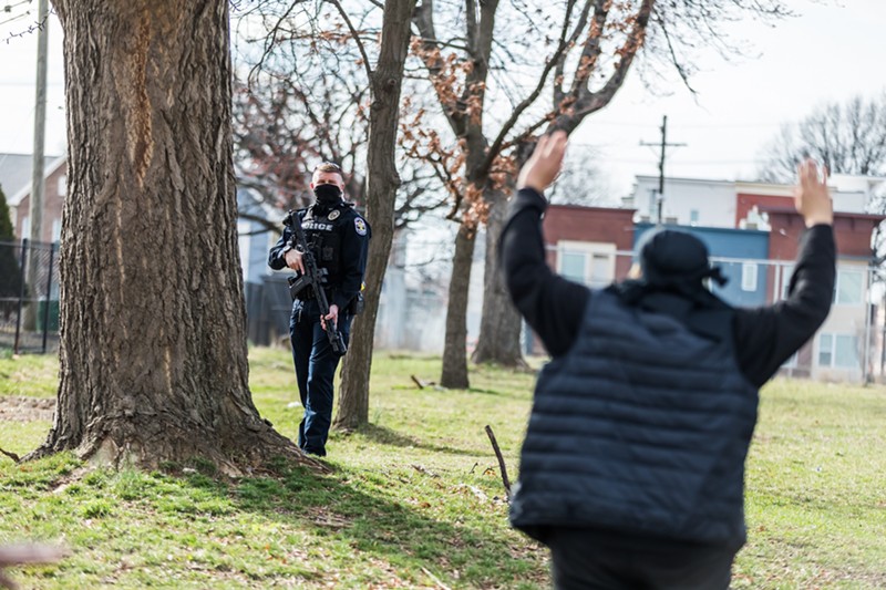 A protester stood with their hands up as a police officer held a gun while protesters marched through downtown. - KATHRYN HARRINGTON