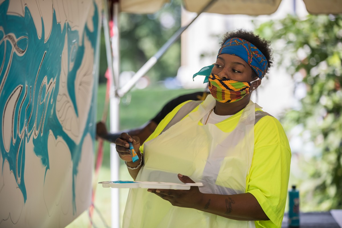 Local artist Precious Stallings worked on a banner honoring Breonna Taylor at the Bre-B-Q event in Shawnee Park on Sunday. - KATHRYN HARRINGTON