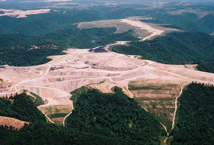 A large surface mining operation above Pigeon Creek in southern West Virginia in the days after a major flood. In the foreground are valley fills, where waste rock is placed after mountaintops are blown up to get at coal. Piles of coal can be seen in the middle of the photo.   |  Photo by Jack Spadaro. - Jack Spadaro