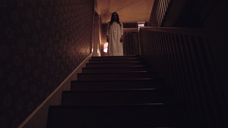 Yes, that's a ghost at the top of the stairs. And she's not happy. Beware.  |  Photo via Christine Ramage/Shudder - John Allman