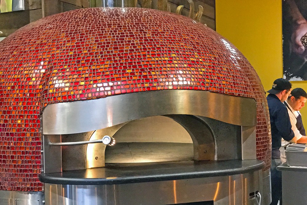 The oversize red-tiled gas- and wood-fired stone oven is a centerpiece of Noosh Nosh&#146;s open kitchen.