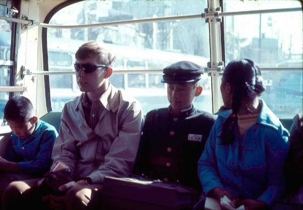 Photo of journalist Bob Edwards sitting on a bus with young Koreans in 1971.