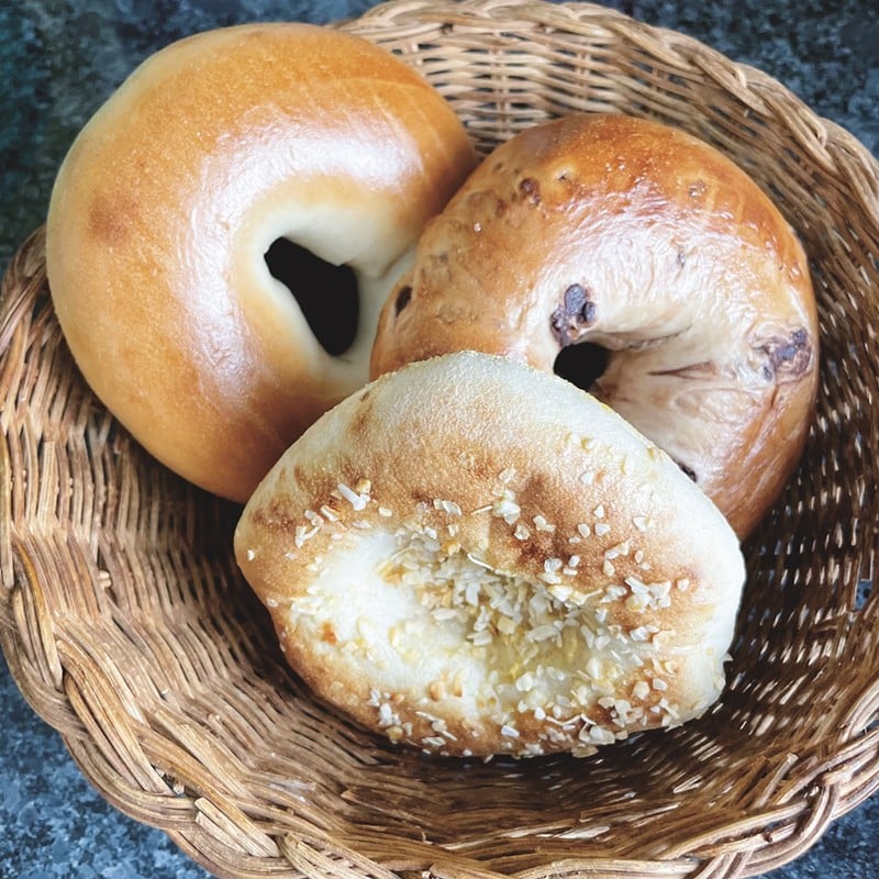 What's a bialy? That's a bialy, right there in front of this takeout trio, a chewy bagel with a dent instead of a hole. At the rear, plain bagel on the left and chocolate chip on the right.