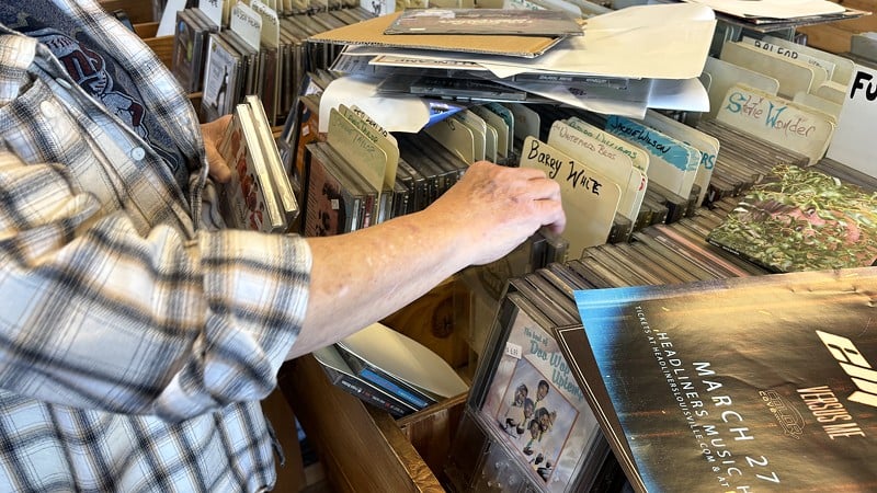 A longtime customer of Underground Sounds browses CDs - Aria Baci
